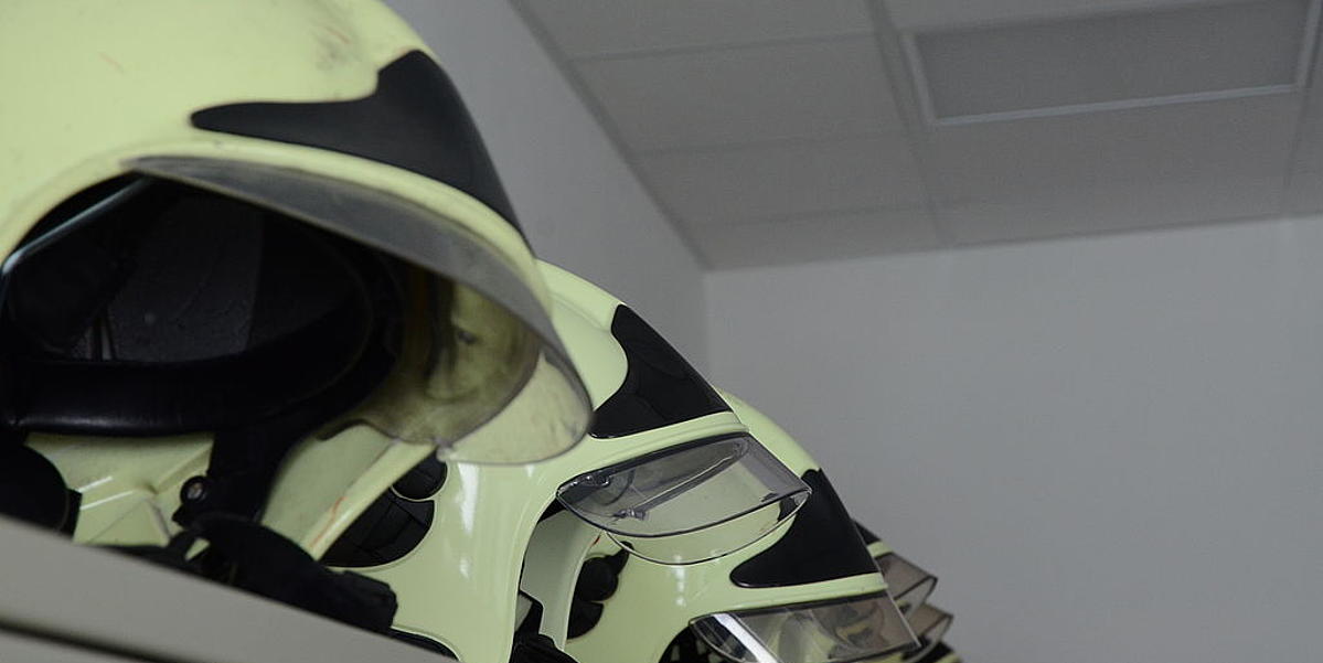 Feuerwehrhelme liegen in einer Reihe auf Spind