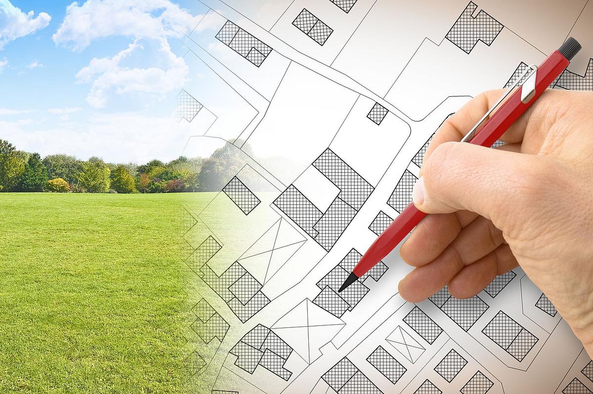 Planung eines neuen Bebauungsgebietes - Konzeptbild mit Handzeichnung einer imaginären Katasterkarte der Fläche mit Gebäuden, Feldern und Straßen vor einer Grünfläche